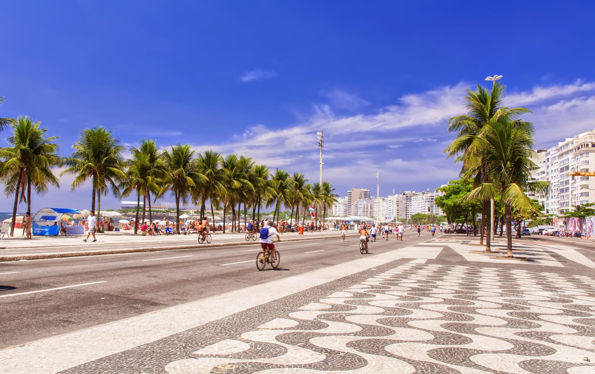 Strand von Copacabana an einem sonnigen Tag mit blauem Himmel, Blick auf das Meer und die Stadt Rio de Janeiro im Hintergrund