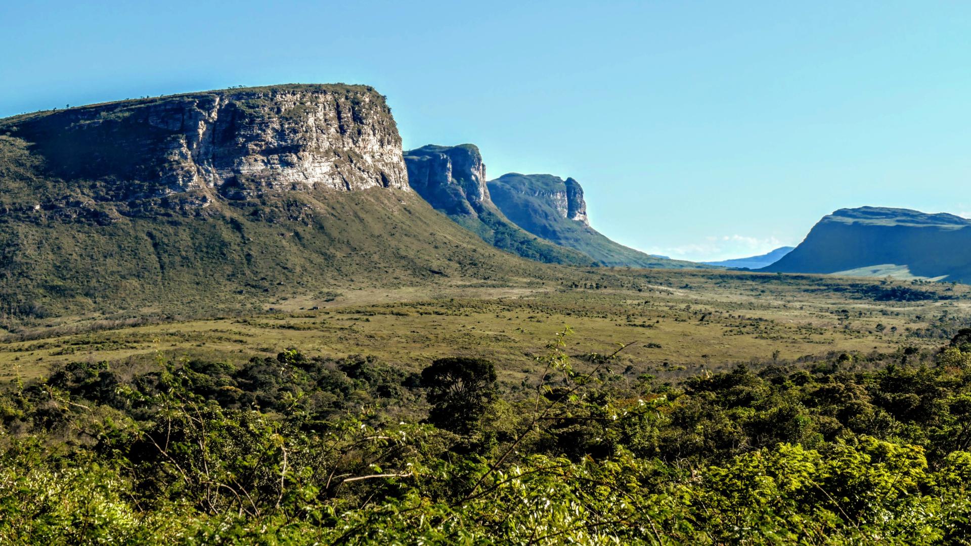 Berglandschaft im Nationalpark Chapada Diamantina, Brasilien, mit grüner Vegetation und markanten Felsformationen unter blauem Himmel.